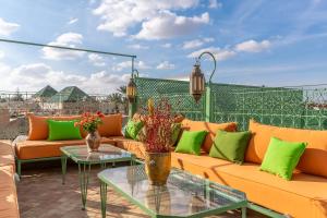 a patio with orange and green furniture and tables at Riad Habouba in Marrakesh