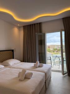 two beds in a hotel room with a balcony at Paraga View in Paraga