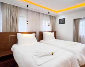 two beds in a hotel room with white sheets at Lusoi Gardens Naromoru in Nyeri +28 photos