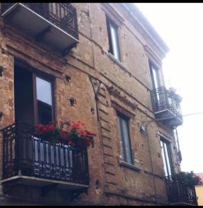 a brick building with balconies and red flowers on it at Affittacamere Isidoro in Zaccanopoli