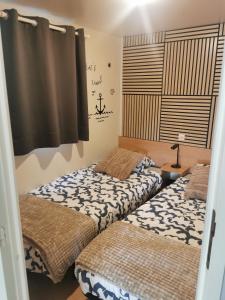 two beds sitting in a room with a window at Mobil-home cosy avec terrasse et jardin privatif in La Bernerie-en-Retz +19 photos