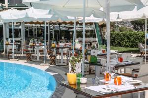 a pool with tables and umbrellas next to a restaurant at Grand Hotel Del Mare Resort & Spa in Bordighera