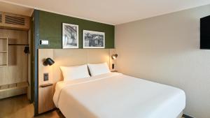 a bedroom with a large white bed in a room at Campanile NATURE - Meaux in Meaux