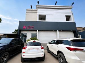 two cars parked in a parking lot in front of a building at Ixoras Hotel Lemba in Kinshasa