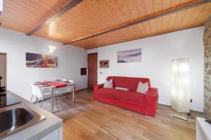 a living room with a red couch and a table at Prima Del Cielo - Alba Apartment in Perledo