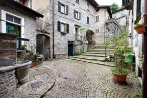 an alley with stone buildings and a potted plant at Prima Del Cielo - Alba Apartment in Perledo