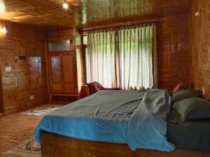 a bed in a wooden room with a window at Monal House in Manāli