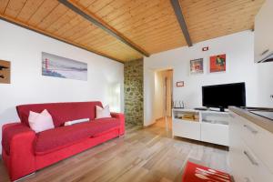 a living room with a red couch and a flat screen tv at Prima Del Cielo - Alba Apartment in Perledo