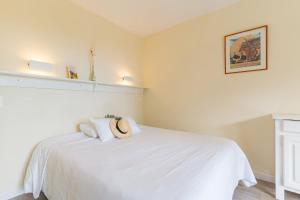 a bedroom with a white bed with a hat on it at Résidences LES HAUTES PLAINES in Gréoux-les-Bains +19 photos