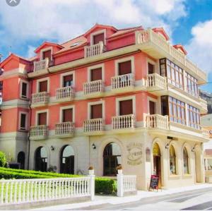 a pink building with a white fence in front of it at Pension Areas in O Pindo