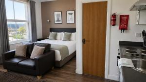 a bedroom with a bed and a chair and a kitchen at Park Hotel & Apartments in Hull