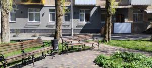 two benches sitting in a park next to trees at Optimal in Vyshneve