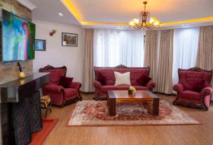 a living room with red chairs and a coffee table at Lusoi Gardens Naromoru in Nyeri