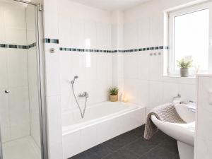 a white bathroom with a tub and a sink at Reetdachhaus 5, inkl 2 Parkplätze in Fehmarn