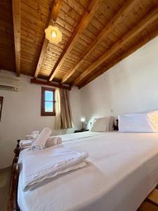 a bedroom with a large white bed with a wooden ceiling at Cleopatra's House Apartments in Archangelos