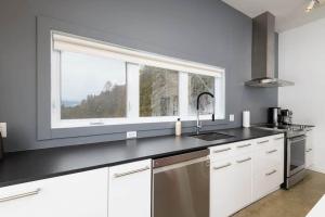 a kitchen with a sink and a large window at Hôtel à la maison - Panache, spa et fleuve in Baie-Saint-Paul