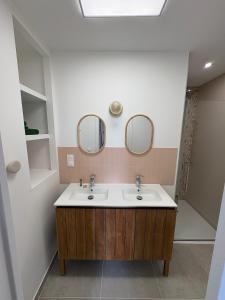 a bathroom with a sink and two mirrors at Chambre d'hôtes Lilas in Saint-Lyphard +9 photos