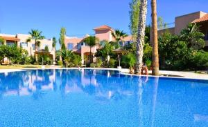 a large blue swimming pool with palm trees and houses at Mandria Gardens Paradise II in Mandria