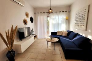 a living room with a blue couch and a tv at Mandria Gardens Paradise II in Mandria