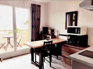 a kitchen with a table and a microwave and a balcony at Virginia N 203 ST2 in Grasse