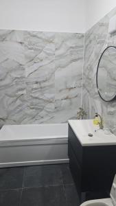 a bathroom with a tub and a sink and a mirror at Vila BELVEDERE in Brăila