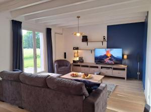 a living room with a couch and a flat screen tv at Maison Céline - Jardin clos et Parking Privé Gratuit in Crevant-Laveine