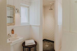 a white bathroom with a sink and a mirror at La Maison du Bassin in Cap-Ferret