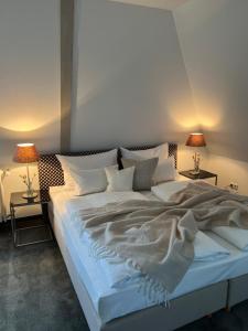 a bedroom with a large white bed with two lamps at Stadt Villa Boutiquehotel in Forchheim