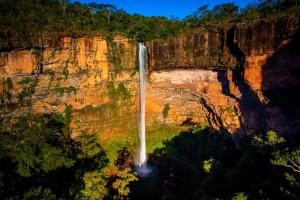 a waterfall on the side of a cliff at Casa charmosa familiar in Chapada dos Guimarães