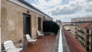 a balcony with white chairs on a building at Apartamentos Azafranal-PARKING GRATIS- in Salamanca