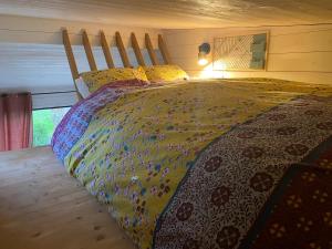 a bed with a colorful comforter in a bedroom at Tiny House de Clara in Avrillé