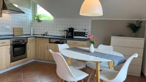 a kitchen with a white table and white chairs at Maarträumchen in Gillenfeld in Gillenfeld