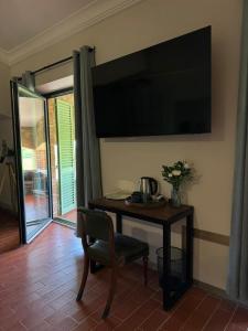 a television on a wall with a table and a chair at Casa M Tuscany in Chianciano Terme
