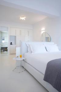 a white bedroom with a large bed and a small table at Blue Vice Megalochori in Megalochori