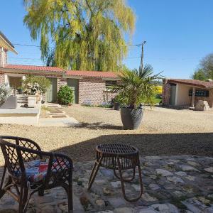 a patio with two benches and a potted plant at Le Gîte Les Grives in Villers-Carbonnel