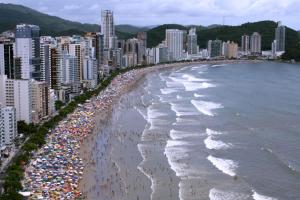een strand met een menigte mensen en de oceaan bij Apartamento Charmoso no Guaruja in Guarujá