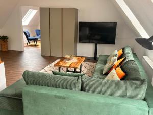 a living room with a green couch and a television at Ferienwohnung Hafenblick in Neumagen-Dhron