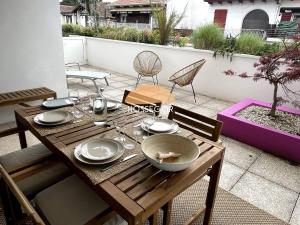 a wooden table with plates and bowls on a patio at Le Clos Brémontier in Soorts-Hossegor