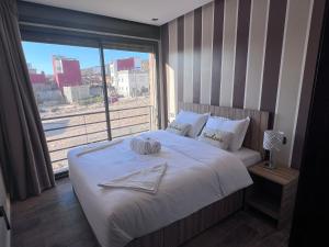 a bedroom with a white bed with a large window at Appartement 3 vue sur mer in Tamraght Ou Fella