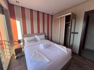 a bedroom with a large white bed with striped walls at Appartement 3 vue sur mer in Tamraght Ou Fella