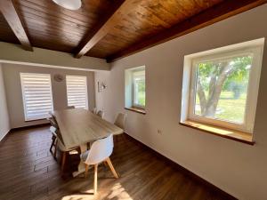 a dining room with a wooden table and two windows at Akácos Tanya Szarvas in Szarvas