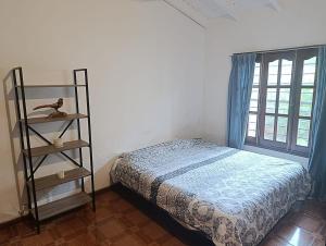 a bedroom with a bed and a book shelf next to a window at Comfortable house in La Falda in La Falda