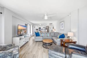 a living room with a couch and a tv at Sandy Bits Oceanfront Premium Condo with Pool in Myrtle Beach +42 photos