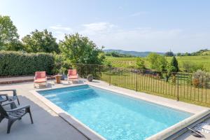 a swimming pool with two chairs and a fence at Villa Lisa in Balazuc