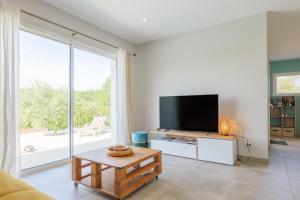 a living room with a tv and a large window at Villa Lisa in Balazuc