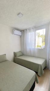 two beds in a room with a window at Aconchego Perto das praias da região oceânica in Niterói +11 photos