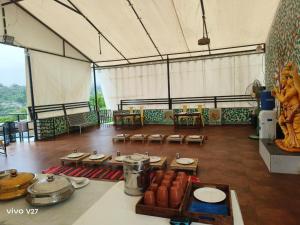 a large room with tables and chairs in a tent at Krishna's den- a cottage retreat a Gaudham Periyar Farmstay in Jambhulpāda