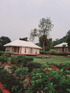 a house in a garden with flowers in the foreground at Krishna's den- a cottage retreat a Gaudham Periyar Farmstay in Jambhulpāda