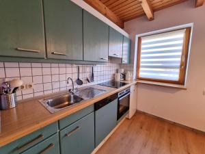 a kitchen with blue cabinets and a sink and a window at Haus 16 im Natur Ferienpark, Natur, Abenteuer und Entspannung für unvergessliche Urlaubstage in Nieheim