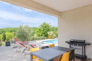 a patio with a table and chairs and a swimming pool at Villa Flora in Balazuc